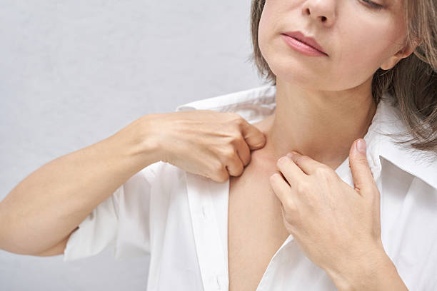 Mature caucasian woman massaging lymph nodes with graceful ease against neutral background.
